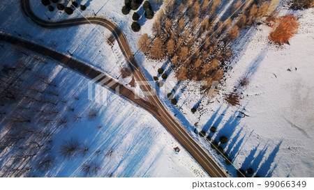 A winding bike path in a city park. City park in winter. Snow lies on the ground. Aerial photography. 99066349