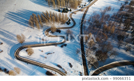 A winding bike path in a city park. City park in winter. Snow lies on the ground. Aerial photography. 99066351