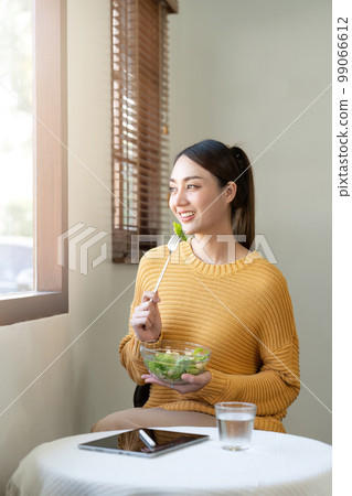 Delighted woman eating food for health at home Delighted woman eating food for health at home 99066612