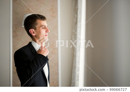 Grooms morning preparation. Handsome man getting dressed and preparing for the wedding Grooms morning preparation. Handsome man getting dressed and preparing for the wedding 99066727