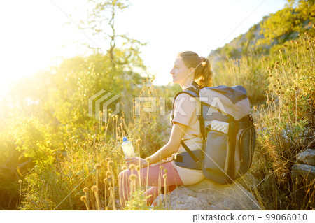 Young woman hiking in countryside. Concepts of adventure, extreme survival, orienteering. Single travel. Backpacking 99068010