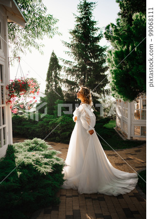 beautiful bride in a white delicate dress walks in the park at sunset. beautiful bride in a white delicate dress walks in the park at sunset. 99068111