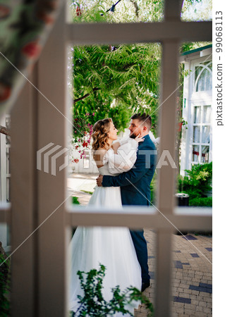 view through the window of a loving couple of newlyweds in the park. view through the window of a loving couple of newlyweds in the park. 99068113