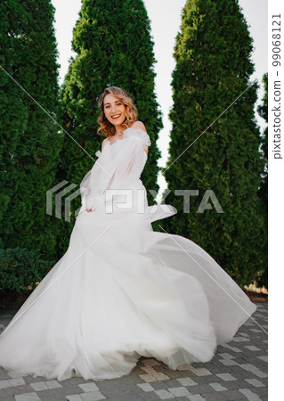 beautiful bride in a white delicate dress dances and spins in the park.  99068121