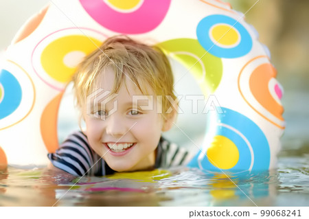Little boy swimming with colorful floating ring in sea on sunny summer day. Cute child playing in clean water. Family and kids resort holiday during summer vacations. 99068241