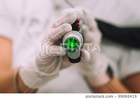 Close up shot of gloved hand with the laser hair removal machine's handpiece. Alexandrite laser techhnology removing hair. Close up shot of gloved hand with the laser hair removal machine's handpiece. Alexandrite laser techhnology removing hair. 99068419