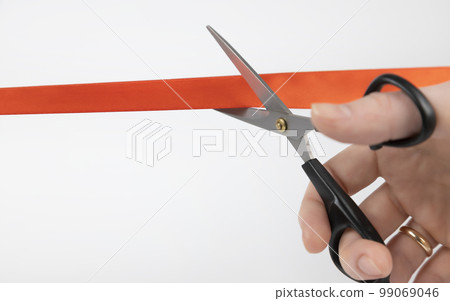 Cutting the red ribbon. Close-up of a woman's hand cutting a red ribbon with scissors 99069046