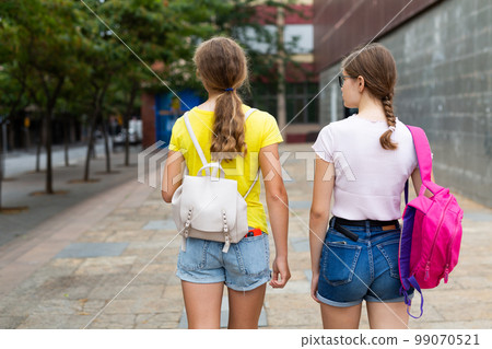 Young students girls walking down the street with a backpack.  99070521