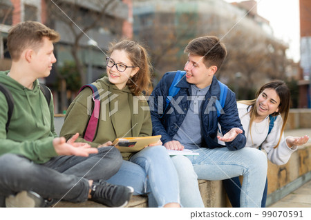Teen friends sitting and talking outdoors Teen friends sitting and talking outdoors 99070591