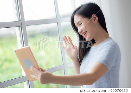 Happiness young asian woman video call with digital tablet in the living room at home. 99070653