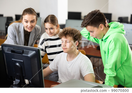Teacher and classmates using computer during lesson 99070800