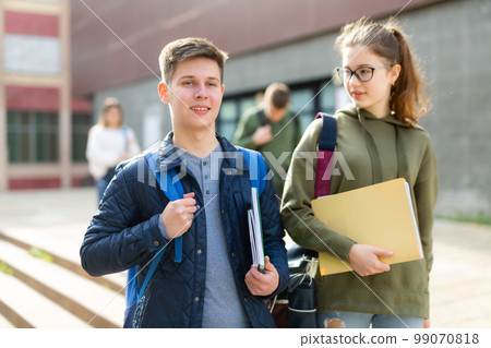 Smiling teenagers walking outside after lessons Smiling teenagers walking outside after lessons 99070818