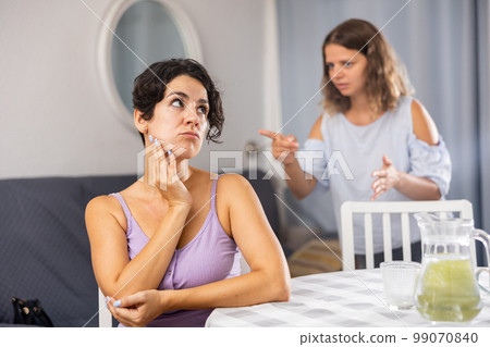 Displeased woman and her female companion, purse lips with displeasure, have quarrel 99070840