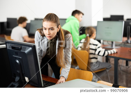 Focused woman sitting at table in computer room in public library 99070906