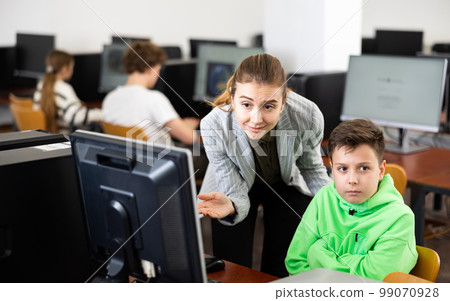 Female teacher and teenage boy looking at monitor of PC 99070928