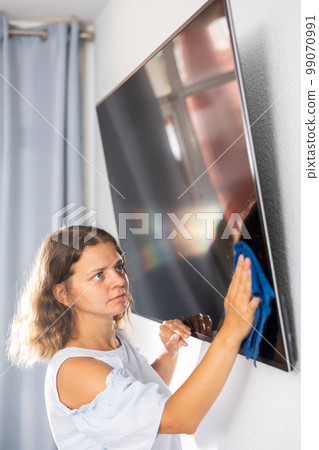 Woman doing housework - washing TV screen with dishcloth 99070991