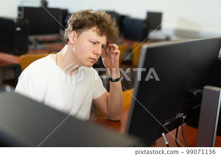 Thoughtful teenager boy using PC during computer science lesson 99071136