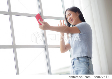 Happiness young asian woman video call with smartphone in the living room at home. Happiness young asian woman video call with smartphone in the living room at home. 99072312