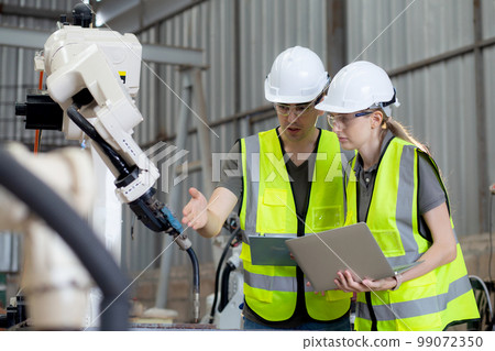 Engineer man and woman talking and explaining about robot arms technology. Engineer man and woman talking and explaining about robot arms technology. 99072350