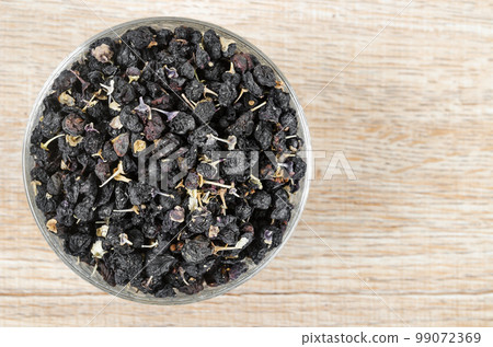 The Black wolfberries or black goji berries, in a wooden bowl on table. 99072369
