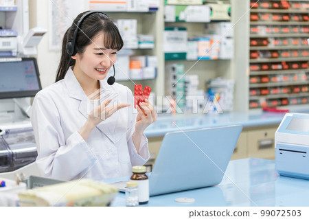 A pharmacist/dispenser woman (prescription/doctor) who provides online medication guidance/medical treatment using a computer at a hospital/pharmacy 99072503