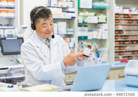 Male pharmacist/dispenser (prescription/doctor) who provides online medication guidance/medical treatment using a computer at a hospital/pharmacy 99072508