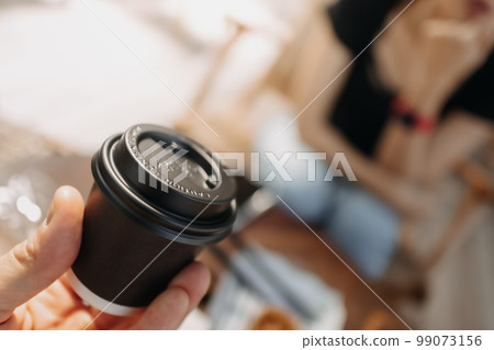 Presenting black cup of hot coffee in a cafe. Presenting black cup of hot coffee in a cafe. 99073156