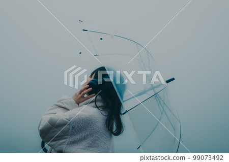 城市背景下撐著雨傘聽音樂的女人照片 99073492