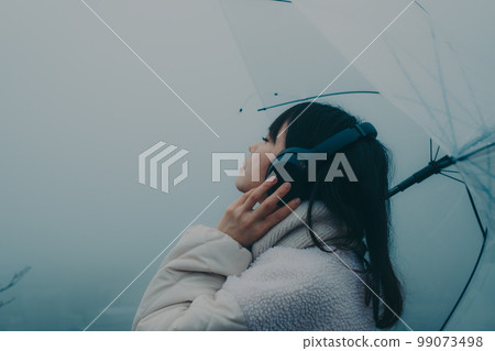 城市背景下撐著雨傘聽音樂的女人照片 99073498