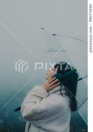 城市背景下撐著雨傘聽音樂的女人照片 99073499