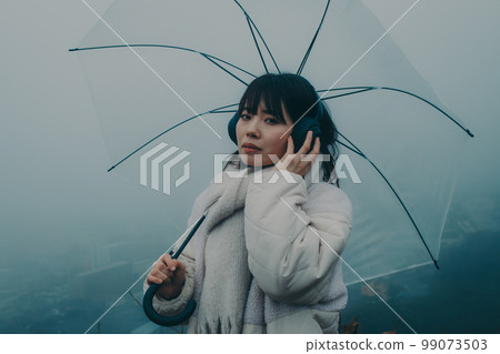 城市背景下撐著雨傘聽音樂的女人照片 城市背景下撐著雨傘聽音樂的女人照片 99073503