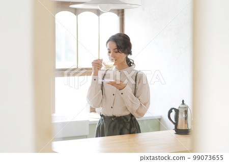A woman drinking a hot drink A woman drinking a hot drink 99073655