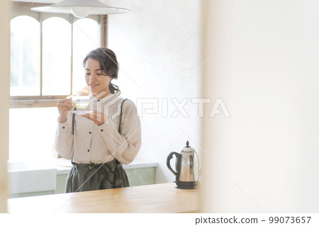 A woman drinking a hot drink A woman drinking a hot drink 99073657