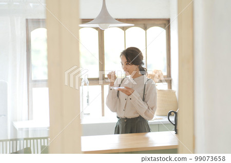 A woman drinking a hot drink 99073658