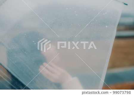 A photo of a woman holding an umbrella on a riverbed and using her smartphone 99073798