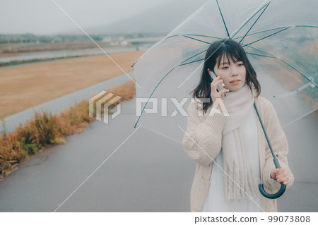 一張女性在河床上打傘並使用智能手機的照片 一張女性在河床上打傘並使用智能手機的照片 99073808