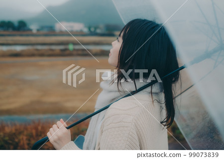 A photo of a woman holding an umbrella on a riverbed and using her smartphone A photo of a woman holding an umbrella on a riverbed and using her smartphone 99073839