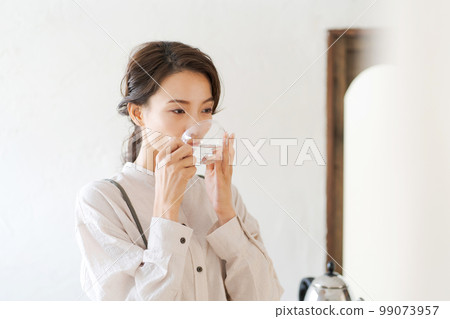 A woman drinking hot water A woman drinking hot water 99073957