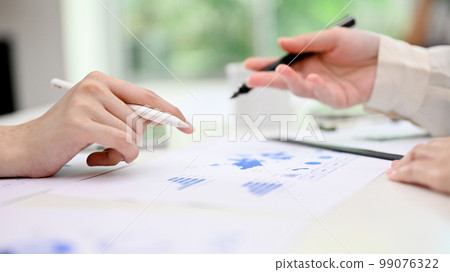 Two businesspeople discussing, analyzing financial data and working on report in the office. Two businesspeople discussing, analyzing financial data and working on report in the office. 99076322