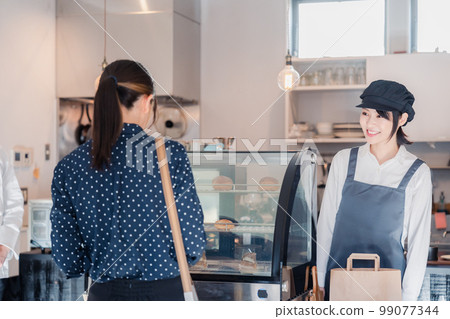 A young woman shopping at a sweets shop with a nice atmosphere 99077344