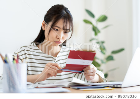 A woman who is worried about looking at her bankbook due to inflation 99078036