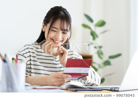 A woman checking a bankbook with inflation 99078043