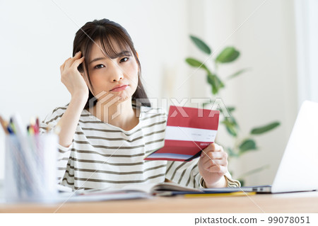 Woman checking household account book with inflation 99078051