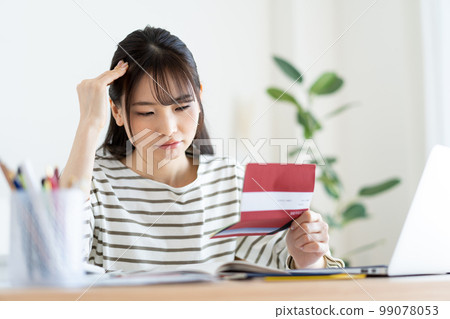 Woman checking household account book with inflation 99078053