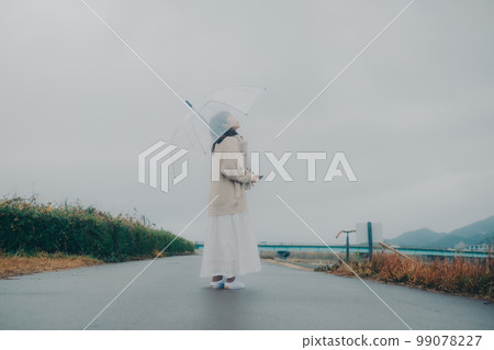 Photo of a woman holding an umbrella by the riverbed Photo of a woman holding an umbrella by the riverbed 99078227