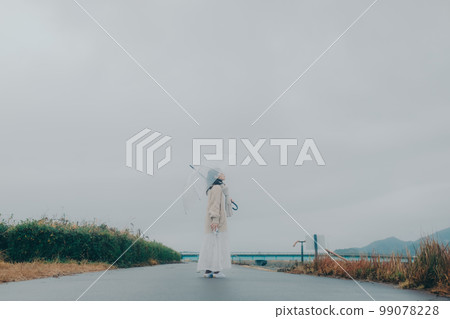 Photo of a woman holding an umbrella by the riverbed Photo of a woman holding an umbrella by the riverbed 99078228