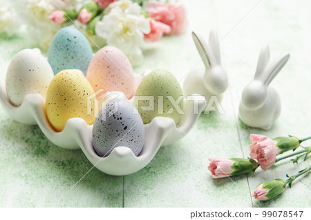 Easter decor. Colored Easter eggs on a ceramic stand and decorative rabbits. Easter decor. Colored Easter eggs on a ceramic stand and decorative rabbits. 99078547