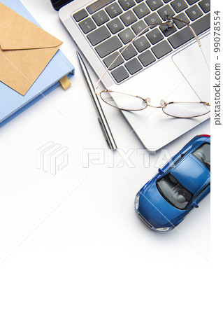 Modern white office desk table with laptop, notebook, toy car and other supplies. Modern white office desk table with laptop, notebook, toy car and other supplies. 99078554
