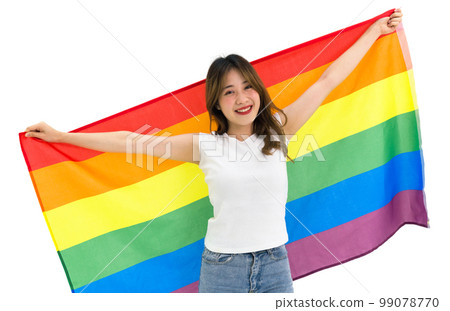 Young asian female LGBTQ stand  smiling, holding big rainbow gay pride unity flag showing same sex love equality. Portrait on white background with studio light. LGBTQ Lifestyle Pride Month 99078770