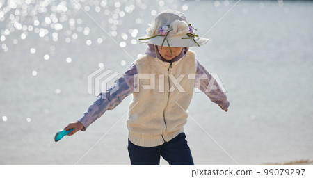 Elementary school girl playing with sand on the beach in winter 99079297